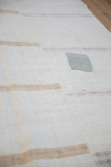 A silver-gray patch adding character to the textured weave of a distressed hemp kilim.