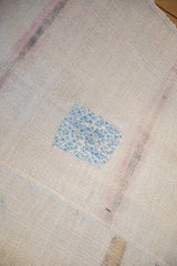 Decorative blue floral patch on the textured cream weave of a vintage hemp kilim.