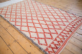 Textured ivory pile with cherry red lattice pattern and small plant motifs, showing an oxidized silver side selvage.