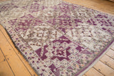 Violet and apricot geometric guls with visible knot heads on a vintage Moroccan carpet.