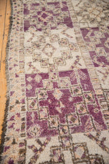 Textured hand-knotted Moroccan carpet pile shows violet, ivory geometric guls, and pinwheel elements.