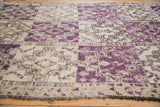 Textured vintage Moroccan carpet pile with repeating violet geometric guls and fringe.