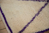 Hand knotted Moroccan rug pile with diagonal violet pattern on an ivory background.