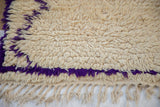 Fluffy ivory pile, vibrant violet purple pattern detail, and fringe on a Moroccan rug.