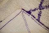 View of the Moroccan carpet's ivory flatweave foundation with violet lines and shaggy pile.