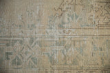 Mostly even wear across the knot heads of a distressed carpet in cream and dusty sea foam green.