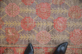 Antique Distressed Khotan rug's faded floral blossoms, revealing purple, red, and gold tones.
