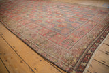 Distressed Khotan runner with faded pale cherry red floral blossoms and intricate border motifs.