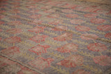 Textured Khotan runner detail: faded cherry red blossoms and dusty gold vinery on a worn aubergine field.