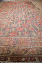 Distressed floral field and restored lower border with faded aubergine and red tones.