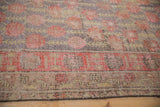 Distressed Khotan rug with faded aubergine floral field and pale cherry red border.