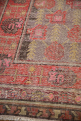 Worn texture of an antique Khotan rug, revealing time-softened red, purple, and gold patterns.