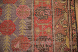 Distressed antique Khotan rug detail: pale cherry red blossoms, dusty purple, aubergine patterns, worn texture.