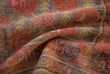 Faded aubergine, pale red, and dusty gold floral blossoms on distressed Khotan rug.