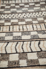 Vintage Moroccan carpet pile showing ivory and black geometric and checkered designs, varied texture.