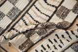 Moroccan carpet detail: varied pile height, ivory, black, and beige geometric patterns.