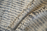 Detail of hand-knotted Moroccan rug with shaggy ivory and charcoal pile, showing abrash.