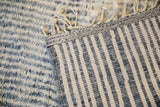 Moroccan rug back showing charcoal and ivory striped foundation with braided fringes.