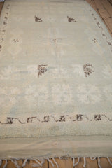 Distressed Moroccan runner's lower edge, with pale seafoam green pile and small holes near fringe.