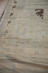 Vintage distressed Moroccan rug pile with pale green and dark brown geometric motifs.
