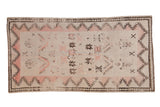 Vintage distressed Moroccan rug runner with starburst motifs and serrated borders in pale rose, brown, and ivory.