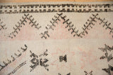 Distressed texture of a vintage Moroccan rug with visible knot heads and exposed ivory foundation.