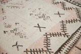Texture of a distressed Moroccan rug with visible knot heads, foundation, and brown geometric patterns.