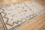 Vintage Moroccan runner shown from an angle, highlighting its distressed texture and pale rose color.