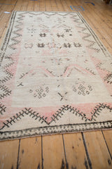 Low angle view highlighting the worn texture and pale rose patterns of a Moroccan runner.