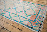 Angled view of vintage Moroccan runner, turquoise chevron vine and dusty blush pink motifs.