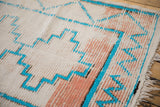 Vintage Moroccan runner's textured cotton white pile, turquoise geometric patterns, visible foundation.