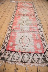Vintage Moroccan runner with blush pink medallions and a dark vine border, seen from a full-length angle.