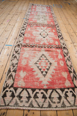 Perspective view down the length of a vintage Moroccan runner with blush and charcoal medallions.