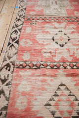 Detail of the dark chocolate brown border alongside the low, blush-pink pile of the rug.