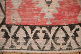 Close view of the textured pile, charcoal geometric border, and blush pink tones.