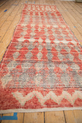 Long perspective view of a vintage Moroccan runner with dusty red and cream geometric patterns.