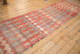 Perspective view of a long Moroccan runner with dusty red diamond motifs and color abrashes.