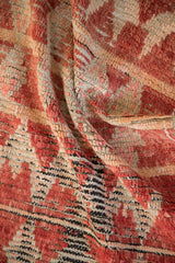 Knot heads and foundation visible between the dusty red and cream hand-knotted pile.
