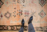 Plush, even pile of a Moroccan carpet with cantaloupe tones and dark brown geometric diamond medallions.