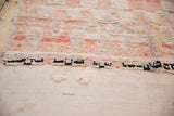 Distressed Moroccan rug showing chunky pile, black-white knot line, and ivory flatweave with pebbles.