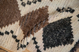 Thick, shaggy ivory, undyed brown, and charcoal pile texture of the Moroccan runner.