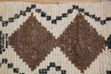 Textured pile of vintage Moroccan rug, highlighting natural brown diamond and ivory pattern.
