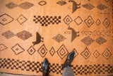 Vintage Moroccan rug's shaggy pale tangerine orange pile with dark chocolate brown bird and geometric designs.