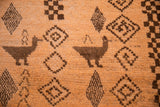 Dark brown ducks and geometric diamonds on a tangerine orange vintage Moroccan rug.