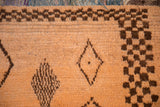 Vintage Moroccan rug detail: pale tangerine field, dark chocolate checkered border, geometric diamond motifs.