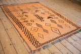 Textured tangerine vintage Moroccan rug, featuring brown geometric diamond motifs and stylized birds.