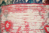 Detail of the vintage Moroccan rug's textured pile, visible red foundation, and multi-colored fringe.