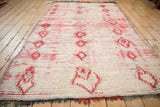 Angled perspective on a vintage Moroccan carpet, highlighting its plush texture and columns of red diamonds.