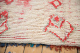 Close view of the hand-knotted ivory pile, red motifs, and colorful fringe edge.