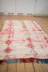 Vintage Moroccan carpet viewed from the end, highlighting its colorful teal, red, and purple fringe.